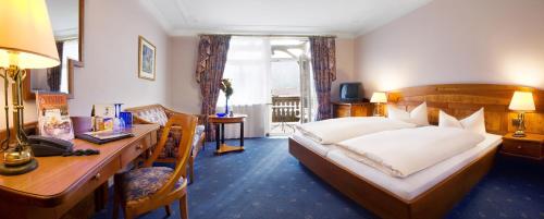 a hotel room with a large bed and a desk at Post-Hotel in Mittenwald