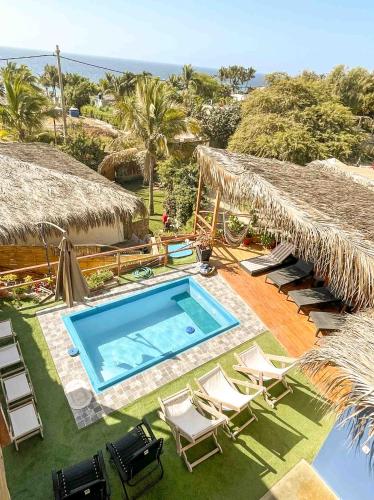 an outdoor swimming pool with chairs and umbrellas at Terrazas Iguana in Máncora