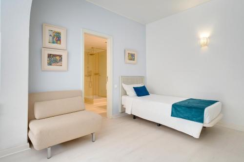 a white bedroom with a bed and a chair at Muthu Clube Praia da Oura in Albufeira