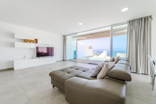 ein Wohnzimmer mit Couch und großem Fenster in der Unterkunft Fabuloso Bungalow con Vista Panorámica y Piscina Privada. in Acantilado de los Gigantes