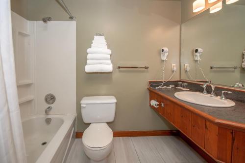 a bathroom with a toilet and a sink and a tub at Painter's Lodge in Campbell River