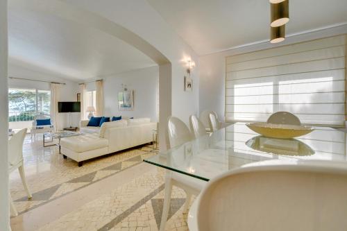 a living room with a glass table and white chairs at Muthu Clube Praia da Oura in Albufeira