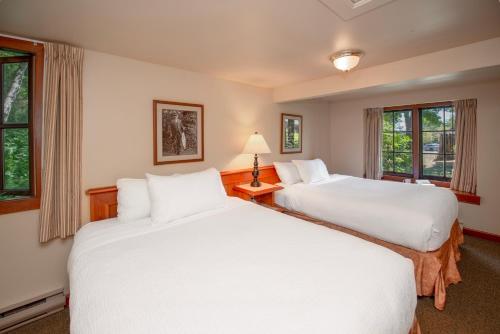 two beds in a room with two windows at Painter's Lodge in Campbell River