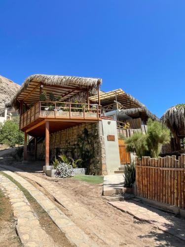 a house with a thatched roof with a porch at Terrazas Iguana in Máncora