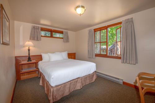 a bedroom with a bed and a desk and windows at Painter's Lodge in Campbell River