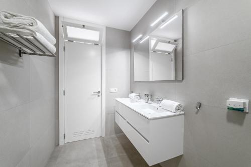 ein weißes Badezimmer mit Waschbecken und Spiegel in der Unterkunft Fabuloso Bungalow con Vista Panorámica y Piscina Privada. in Acantilado de los Gigantes
