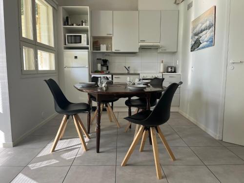 a kitchen with a wooden table and black chairs at Tyylikäs koko perheen huoneisto in Vuokatti