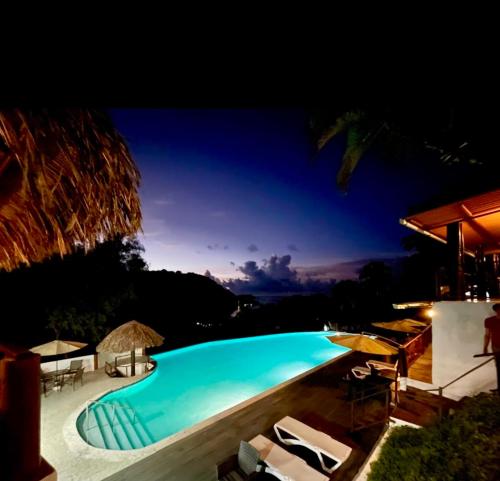 a swimming pool at night with chairs and umbrellas at Ranchos de Chalia Panama in Portobelo