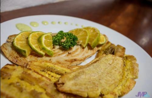 a white plate of food with fish and lemon slices at Ranchos de Chalia Panama in Portobelo