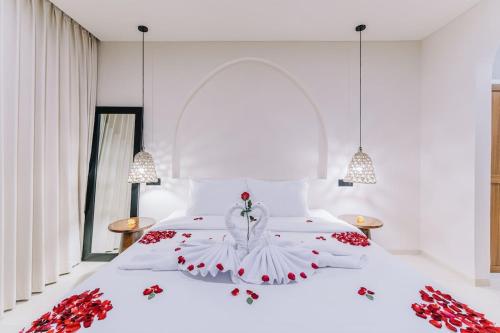 a bedroom with a white bed with red flowers on it at 1BR Balcony Pool Villa Near Seseh Beach in Munggu