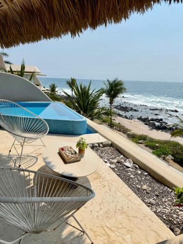 a patio with a table and chairs and the beach at Romantic Mediterranean Escape by the Sea in La Majahua