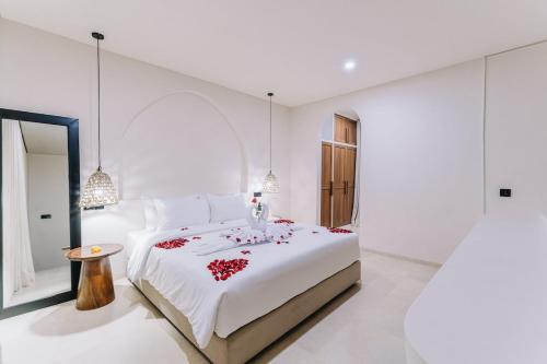 a white bedroom with a large bed with red flowers on it at 1BR Balcony Pool Villa Near Seseh Beach in Munggu