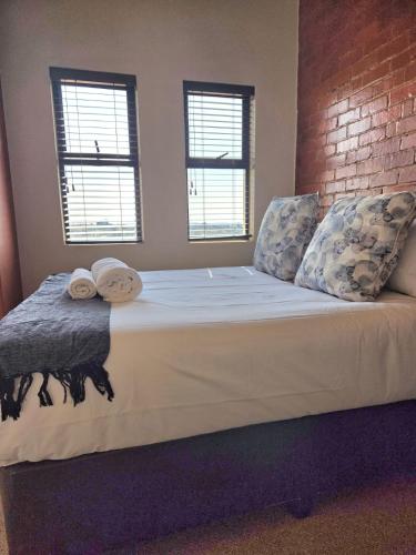 a large bed with two pillows and a brick wall at 1 bed Apartment in hatfield in Pretoria