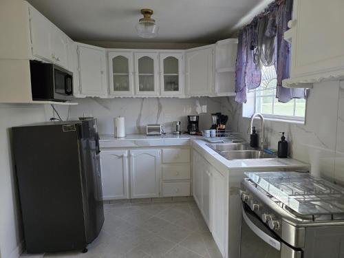 a kitchen with white cabinets and a black refrigerator at Cassywins Short Term Rentals in Christ Church