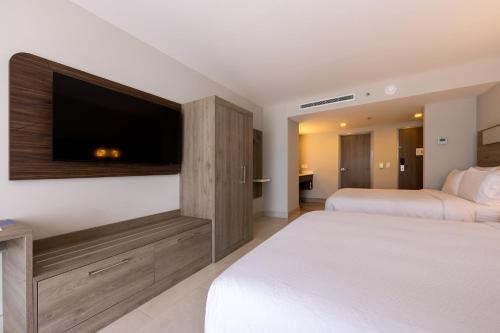 a bedroom with two beds and a flat screen tv at Holiday Inn Express & Suites Mazatlan by IHG in Mazatlán