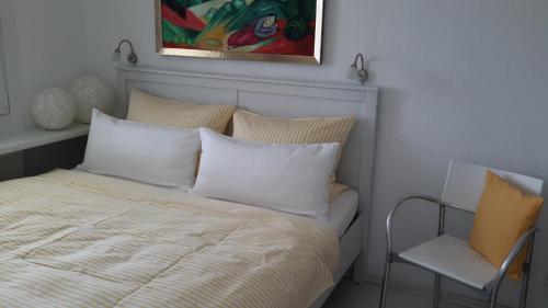 a bed with white pillows and a painting above it at Smucke Stuuv I in Glücksburg