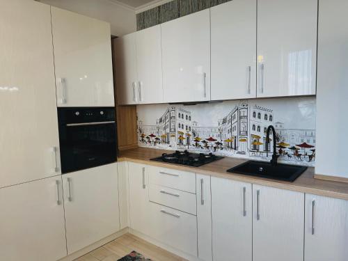a kitchen with white cabinets and a drawing on the wall at Blue Harmony Apartment in Chişinău