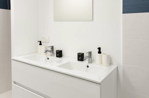 a white bathroom with a sink and a mirror at Maison de Standing 3 Chambres Parking Spacieux in Château-Gaillard