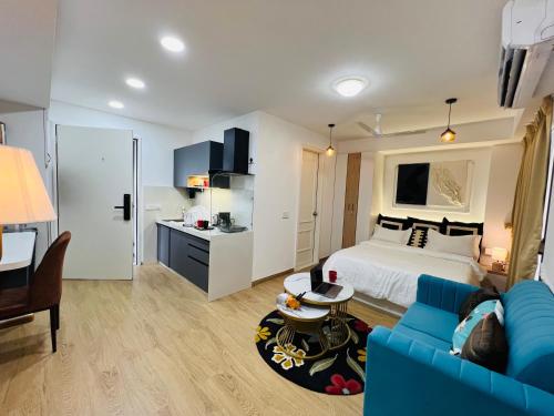 Una sala de estar con una cama y un sofá azul. en Flyora Studio 5min to Airport, en Pune