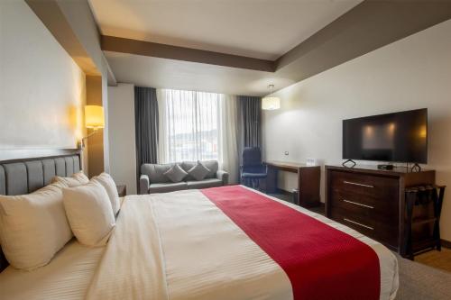 a hotel room with a bed and a flat screen tv at Best Western Plus Santa Cecilia Pachuca in Pachuca de Soto