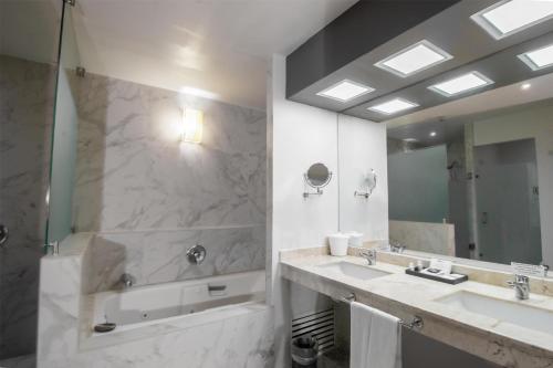 a bathroom with two sinks and a shower and a mirror at Best Western Plus Santa Cecilia Pachuca in Pachuca de Soto