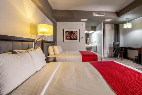 a hotel room with two beds and a desk at Best Western Plus Santa Cecilia Pachuca in Pachuca de Soto