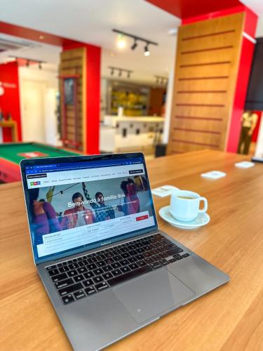 a laptop computer sitting on a table with a cup of coffee at ibis Maceio Pajuçara in Maceió