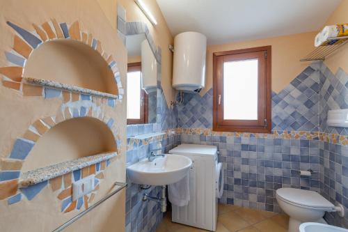 baño de azulejos azules con lavabo y aseo en Appartamento Mare Sardegna Porto San Paolo, en Porto San Paolo