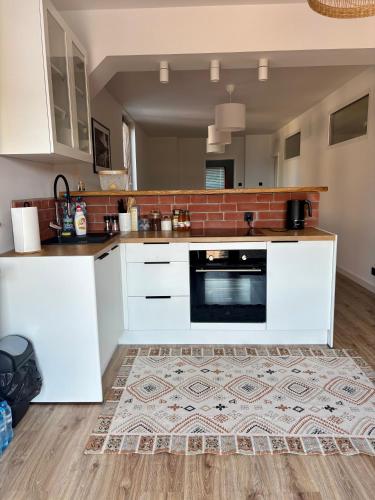 a kitchen with white cabinets and a rug on the floor at Apartament pod Świerkami in Pisz