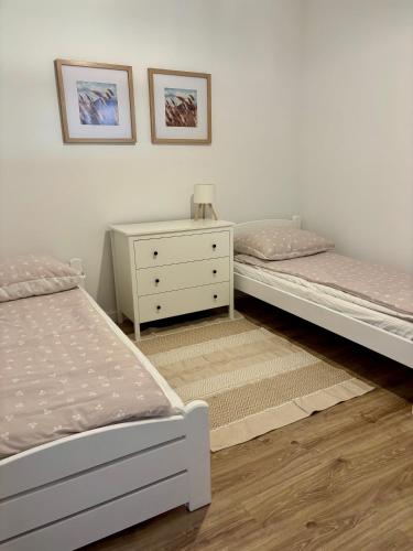 a bedroom with two beds and a dresser and a night stand at Apartament pod Świerkami in Pisz