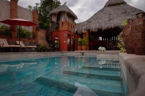a swimming pool with a building with a thatch roof at Casa Miura Hotel Boutique in Ajijic