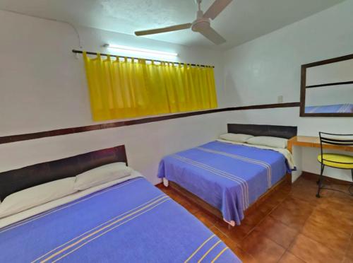 a bedroom with two beds and a table and a window at Hotel Sauces Celaya in Celaya