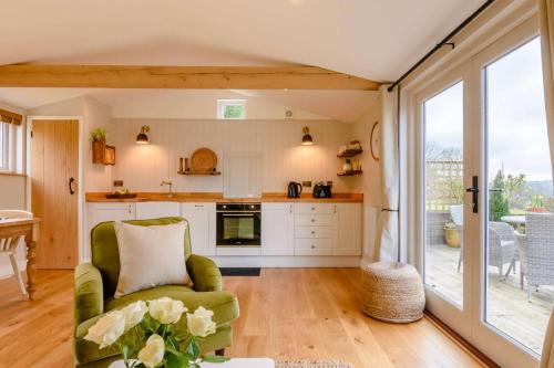 a living room with a green chair and a kitchen at Treetops at Bewl Water in Wadhurst