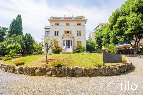 a large white house with a tree in front of it at Villa Aranci | Historical Residence | By Tilo Lux in Genova