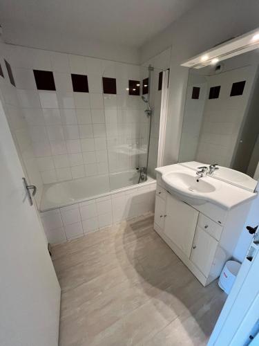 a white bathroom with a sink and a bath tub at Ocean Escape Mimizan Beach in Mimizan-Plage