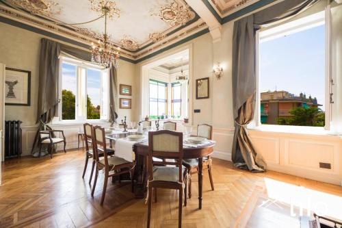a dining room with a table and chairs and windows at Villa Aranci | Historical Residence | By Tilo Lux in Genova