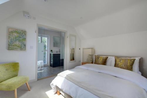a white bedroom with a large bed and a chair at Beech Cottage at Fir House in Cranbrook