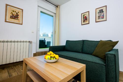 a living room with a couch and a bowl of fruit on a table at Arena Penthouse Apartments in Belgrade