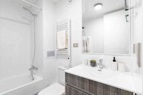 a white bathroom with a sink and a tub and a toilet at Departamento en Chillán in Chillán