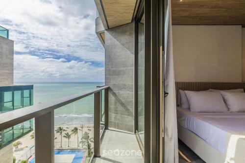 a bedroom with a bed and a view of the ocean at NWTs - Estúdios com Vista Lateral Mar em Maceió IV in Maceió