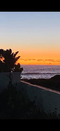 a sunset on the beach with the ocean at Villa Blau -Stunning Beach Front House Grotto Bay Private Nature Reserve West Coast in Grotto Bay
