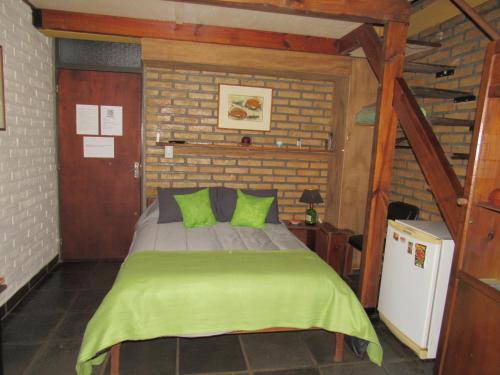 a bedroom with a bed with green pillows at Vitral Cabaña Kindgreen in Oberá