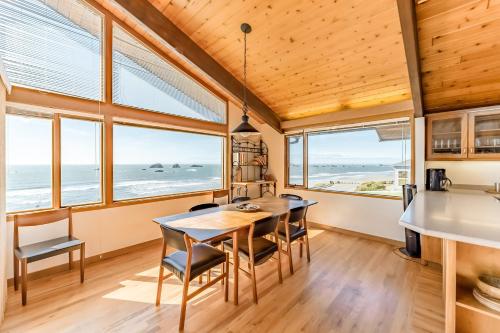 a dining room with a table and chairs and windows at Crown of the Coast in Crescent City