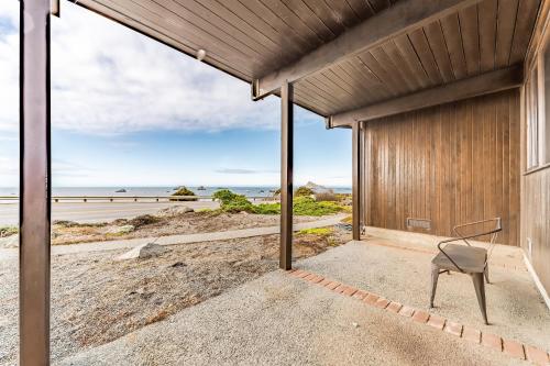a chair sits outside of a building with a view of the beach at Crown of the Coast in Crescent City