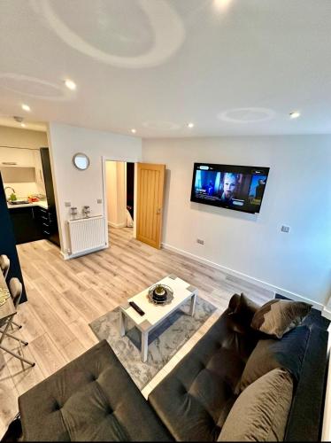 a living room with a couch and a tv on the wall at Modern 2 Bedroom Apartment in City Centre Free Parking with Fast WiFi Near Arena in Nottingham