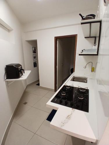 a white kitchen with a stove and a sink at Apartamento á 1200m da Praia de Itapua in Vila Velha