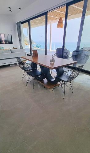 a wooden table and chairs in a room with windows at The Cliff in Melínta