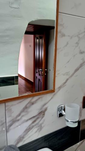 a mirror above a sink with a door in a bathroom at Çelo's house Gjirokaster in Gjirokastër