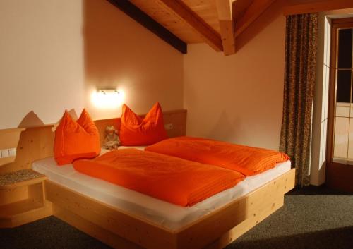 a bedroom with a wooden bed with orange sheets and pillows at Schösserhof in Zell am Ziller