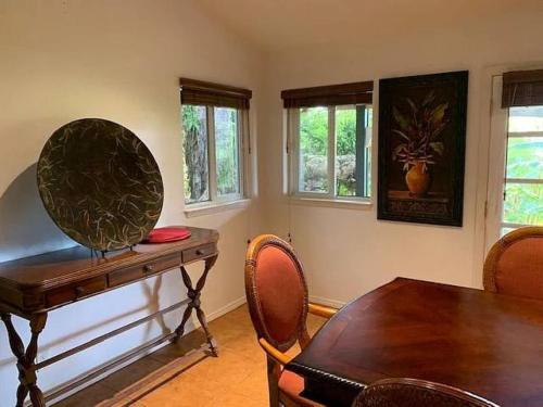 a dining room with a table and chairs and windows at Peaceful Olinda Getaway in Makawao